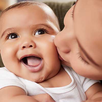 Parent kissing a smiling baby