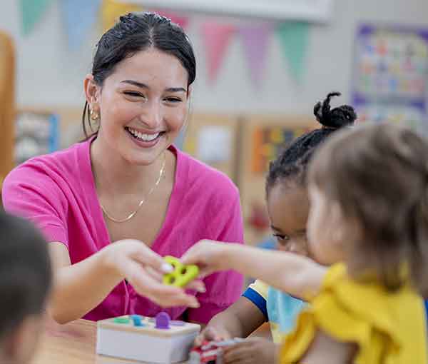 Smiling early childhood educator engaging with a child