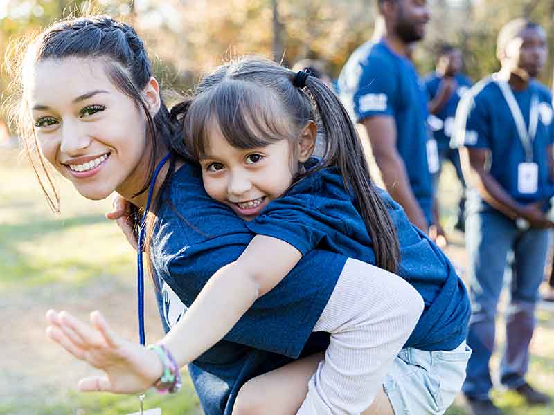 Nevada ECAC Our Vision Mother carrying her daughter piggyback outdoors