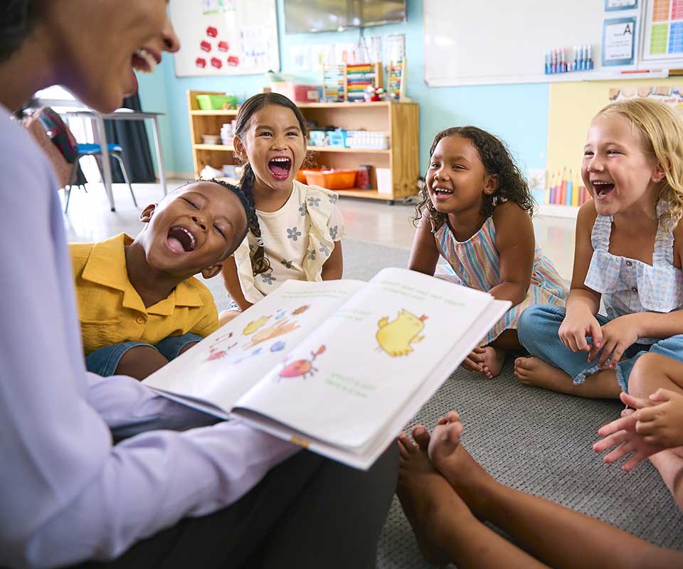Nevada ECAC About Us Early Childhood Professionals Get Involved Educator reading a book and laughing with children