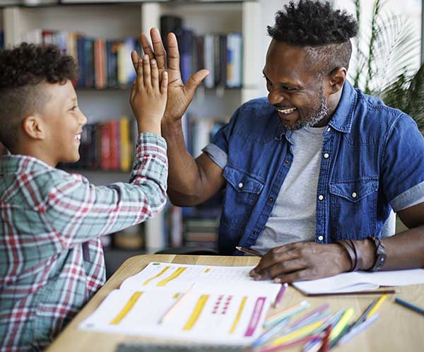 Father and son sharing a high five over a learning activity
