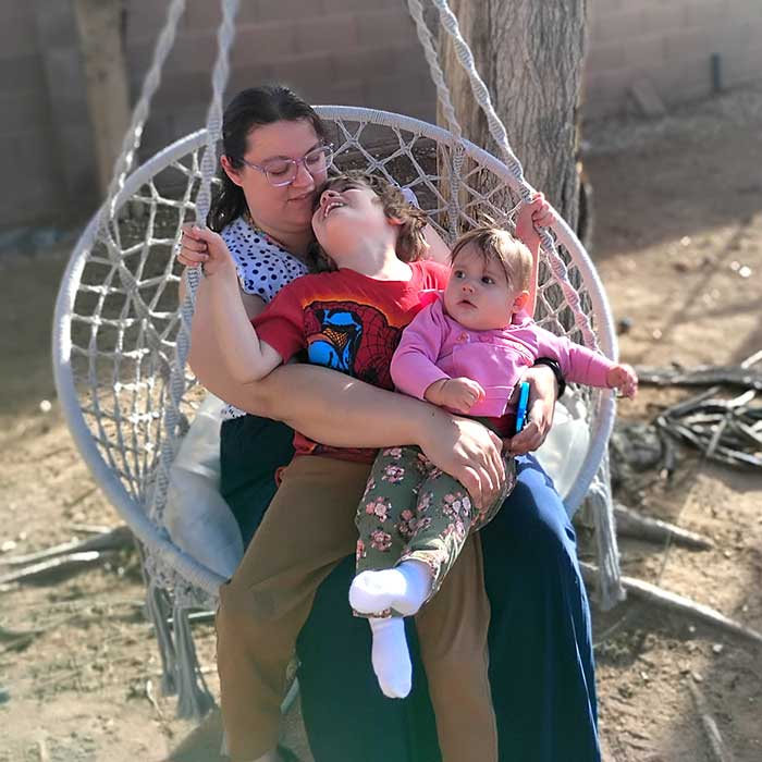 Mother seated in a hanging chair with two young children
