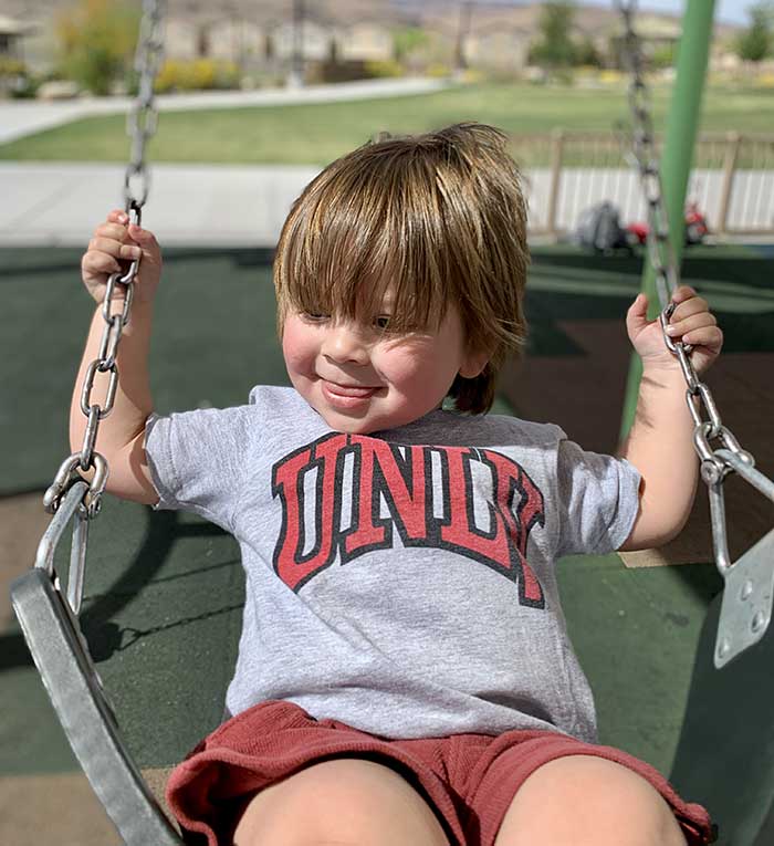 Boy standing beside a playground swing