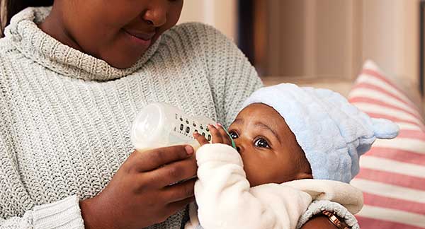Parent feeding a newborn with a bottle