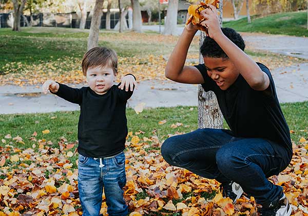 Nevada ECAC General Calendar 1 Young child playing in fallen leaves outdoors