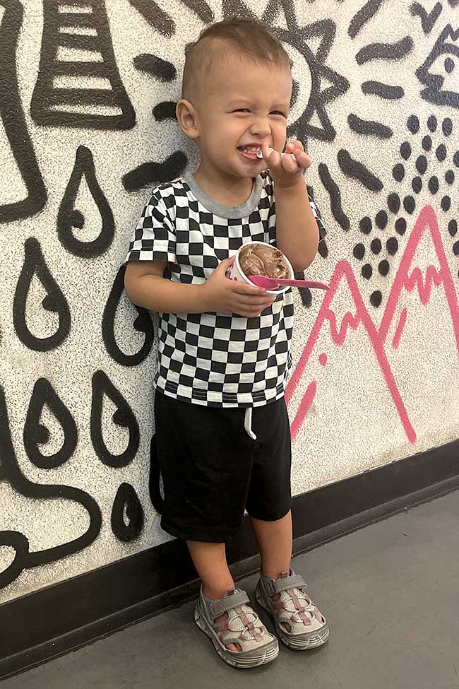Young child standing beside a colorful mural