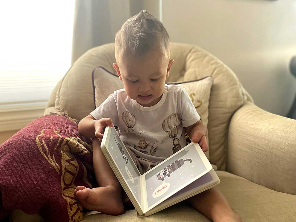 Young child looking at a book or tablet with an adult