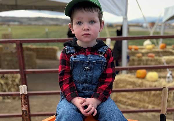 Young child seated outdoors in a plaid shirt